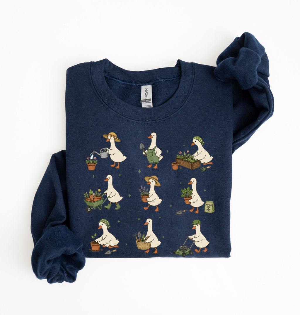 A navy blue long-sleeve sweatshirt with a graphic print of cartoon ducks gardening, shown folded on a white background.