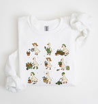 A white long-sleeve crewneck sweatshirt with a graphic print of nine cartoon geese doing gardening activities, laid flat on a white background with a matching white fabric prop.