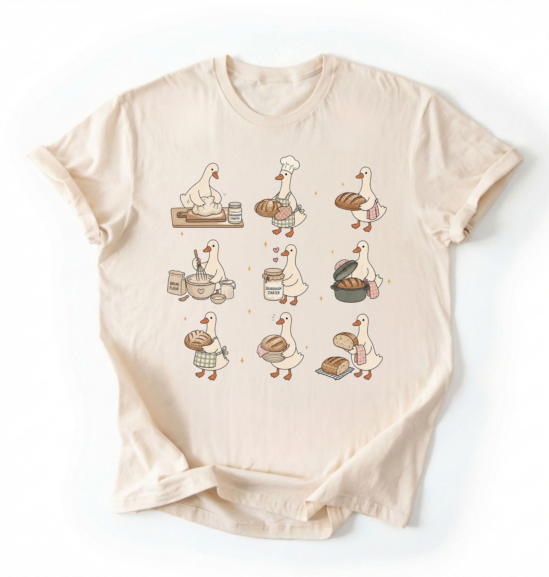 Flat lay of a Cute goose baker shirt with sourdough bread and cottagecore baking artwork on cream tee on a white background 