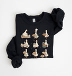 A black long-sleeve sweatshirt with a graphic print of a goose depicted in various cooking and baking poses, styled flat on a white background.