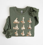 An olive green long-sleeve sweatshirt with a graphic print of nine bakers' ducks in various cooking and baking poses, shown folded on a white background.