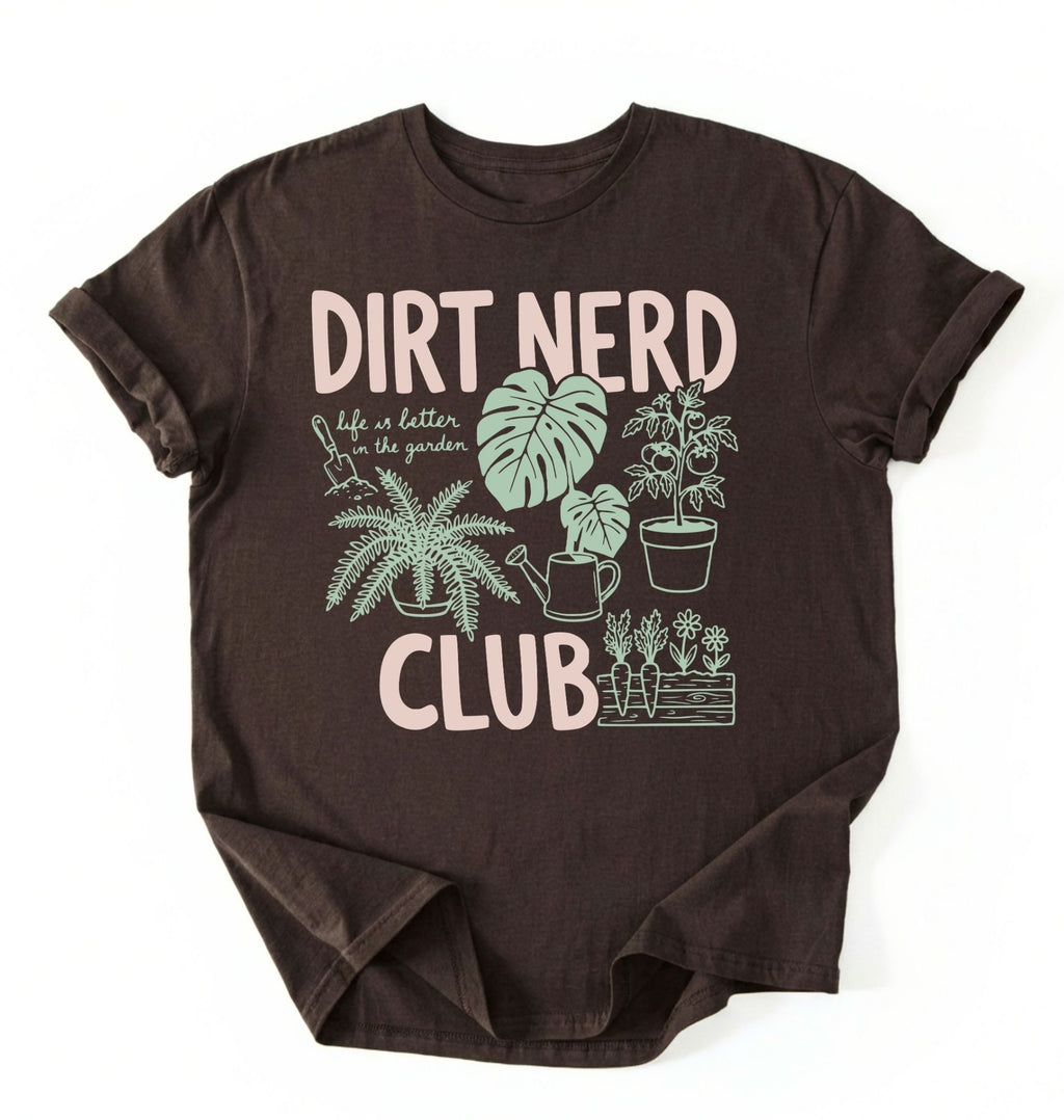 Flat lay of an espresso t-shirt featuring plant illustrations and bold text reading “Dirt Nerd Club.” on a white background