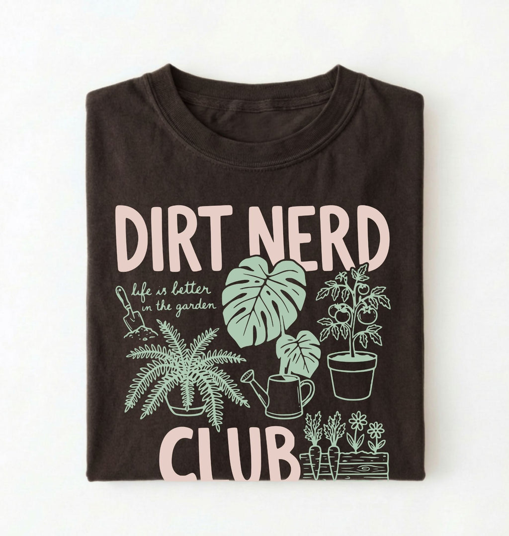 Flat lay of an espresso t-shirt featuring plant illustrations and bold text reading “Dirt Nerd Club.” on a white background