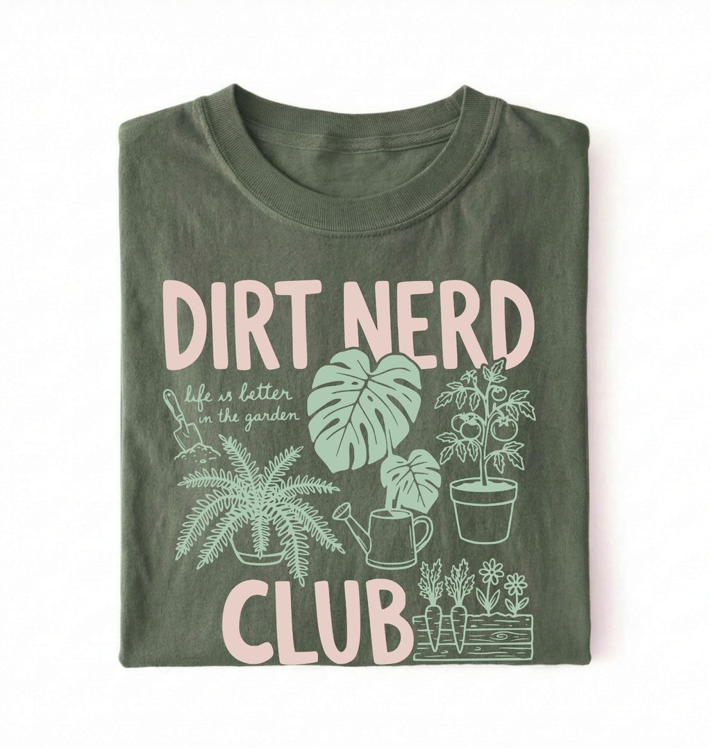 Flat lay of a moss t-shirt featuring plant illustrations and bold text reading “Dirt Nerd Club.” on a white background