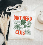 Tote bag with 'Dirt Nerd Club' text and plant illustrations on a textured surface.