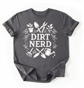 Flat lay of a charcoal Dirt nerd gardening shirt with tools and plant illustrations perfect gift for gardeners and plant lovers on a white background