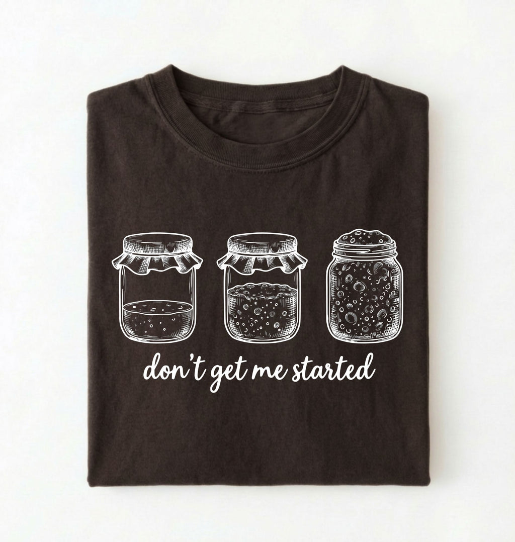 Flat lay of a dark chocolate Funny sourdough shirt with starter jars illustration perfect gift for bakers and fermentation lovers on a white background 