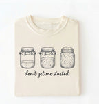 Flat lay of an ivory Funny sourdough shirt with starter jars illustration perfect gift for bakers and fermentation lovers on a white background