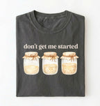 Flat lay of a pepper t-shirt featuring illustrated jars and text reading “Don’t Get Me Started. Funny sourdough starter perfect gift for bakers fermentation lovers and bread enthusiasts on a white background

