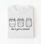 Flat lay of a white Funny sourdough shirt with starter jars illustration perfect gift for bakers and fermentation lovers on a white background
