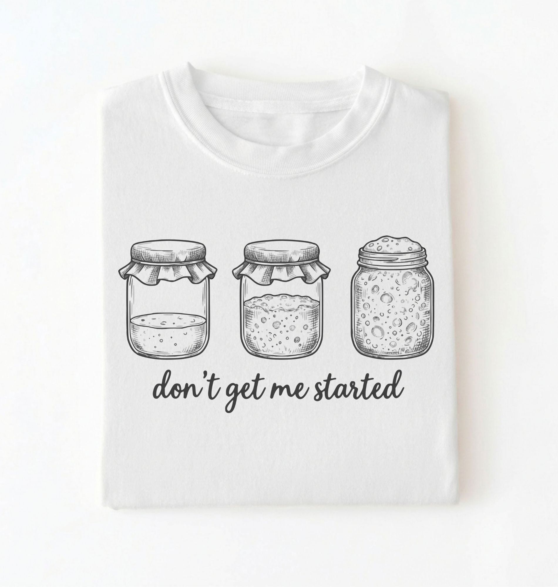 Flat lay of a white Funny sourdough shirt with starter jars illustration perfect gift for bakers and fermentation lovers on a white background