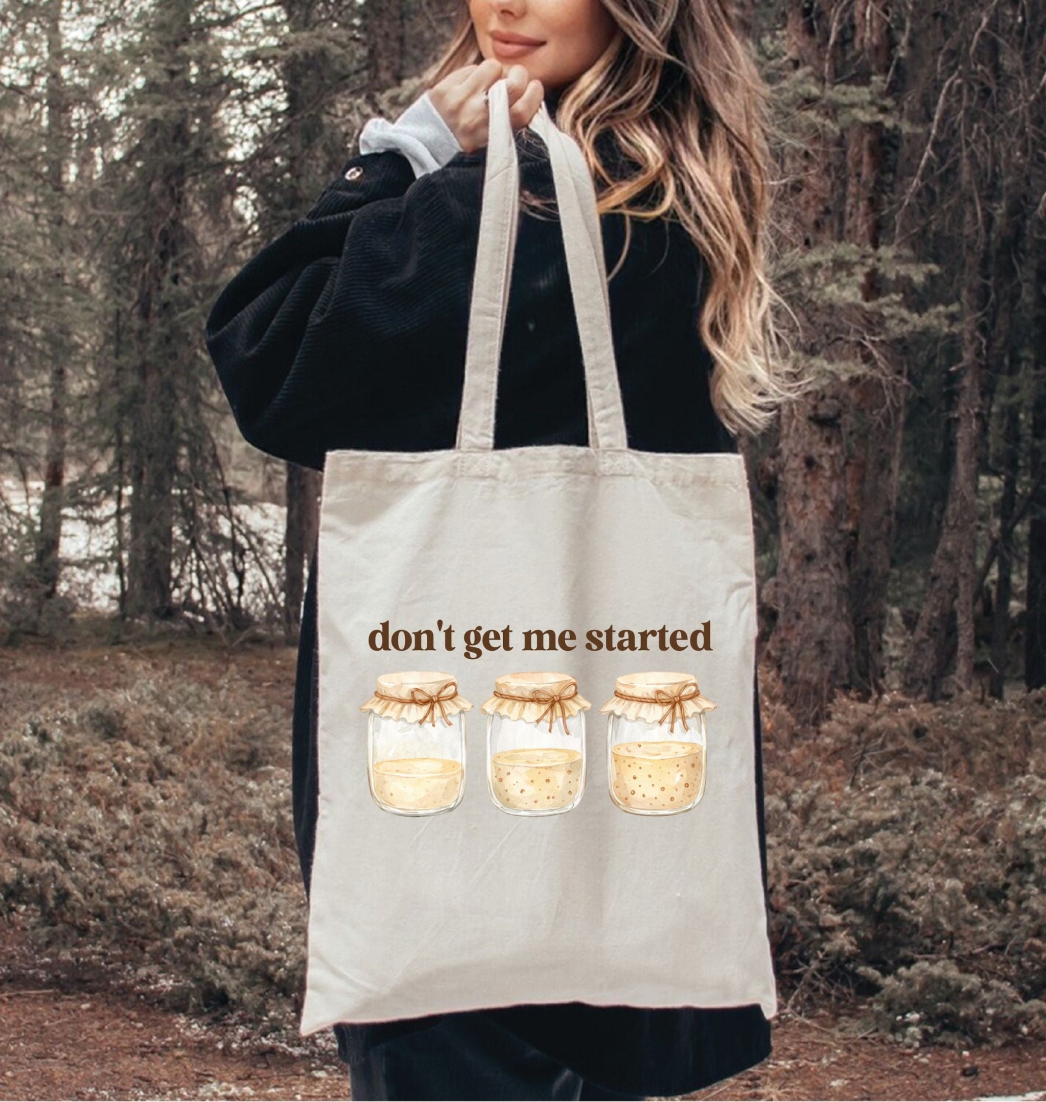 Person holding a tote bag with 'don't get me started' text and jar illustrations in a forest setting