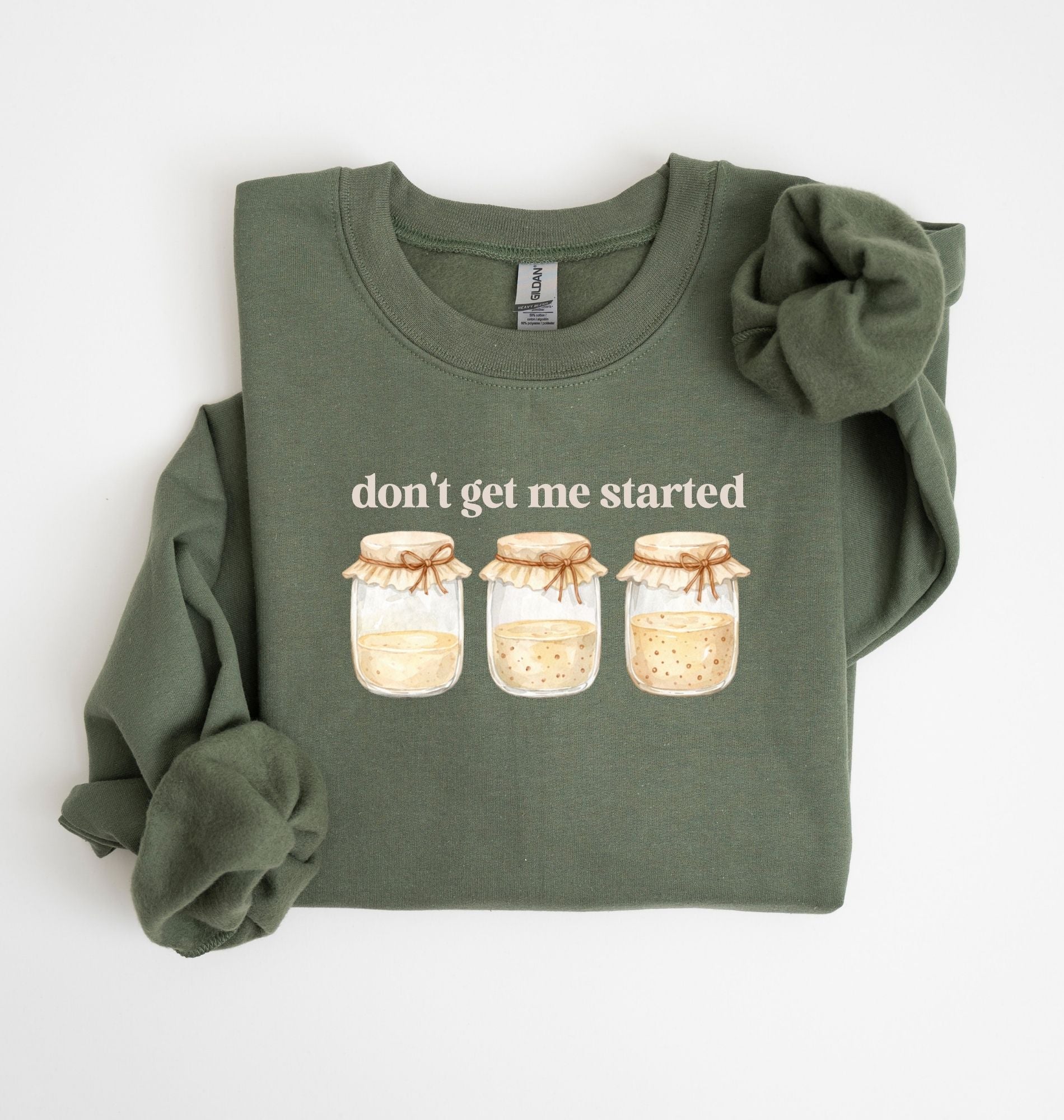Flat lay of a military green Cottagecore kitchen sweatshirt with jars illustration cozy baking lover gift on a white background 