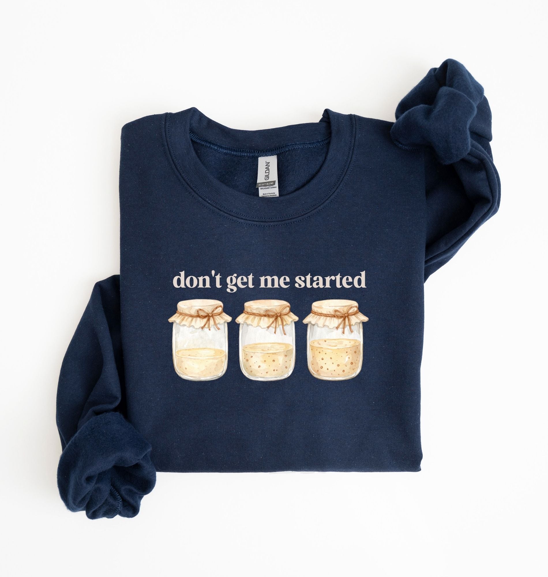 Flat lay of a navy Cottagecore kitchen sweatshirt with jars illustration cozy baking lover gift on a white background 