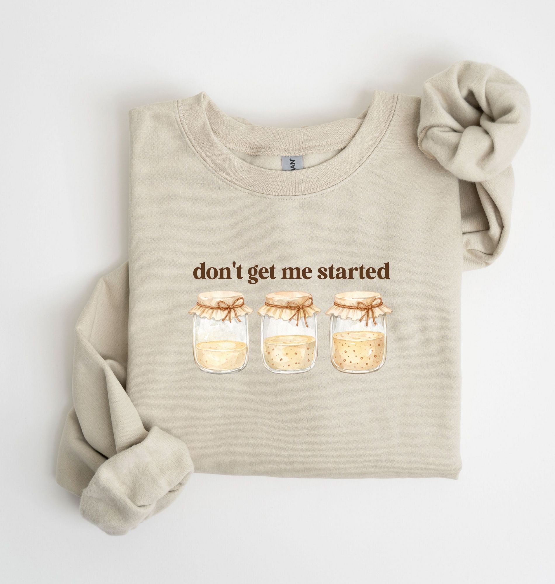 Flat lay of a sand Cottagecore kitchen sweatshirt with jars illustration cozy baking lover gift on a white background 