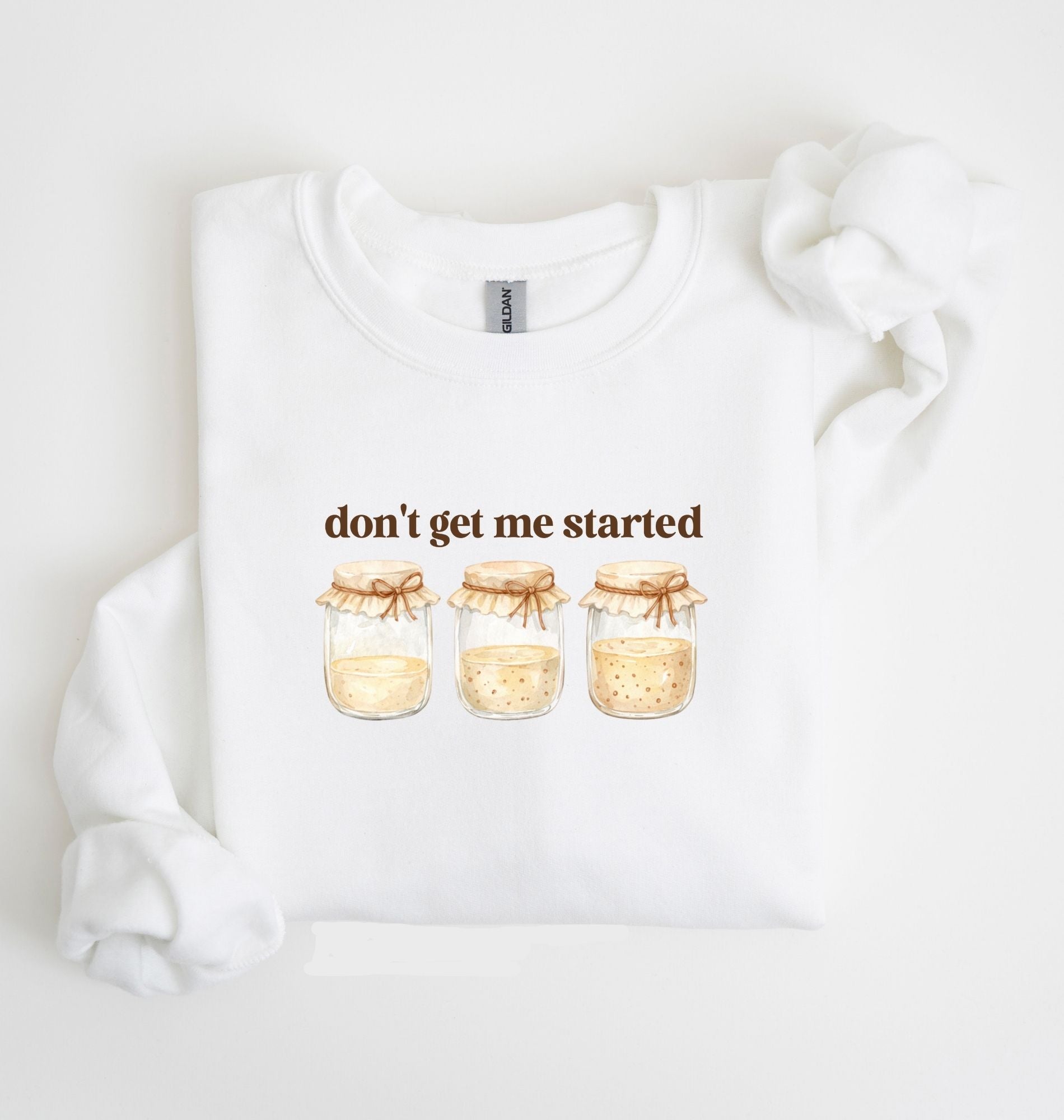 Flat lay of a white Cottagecore kitchen sweatshirt with jars illustration cozy baking lover gift on a white background 