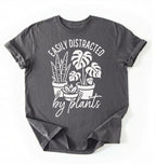 A Charcoal color shirt with a text written "easily distracted by plants" with houseplant illustration plant lover gift on a white background 