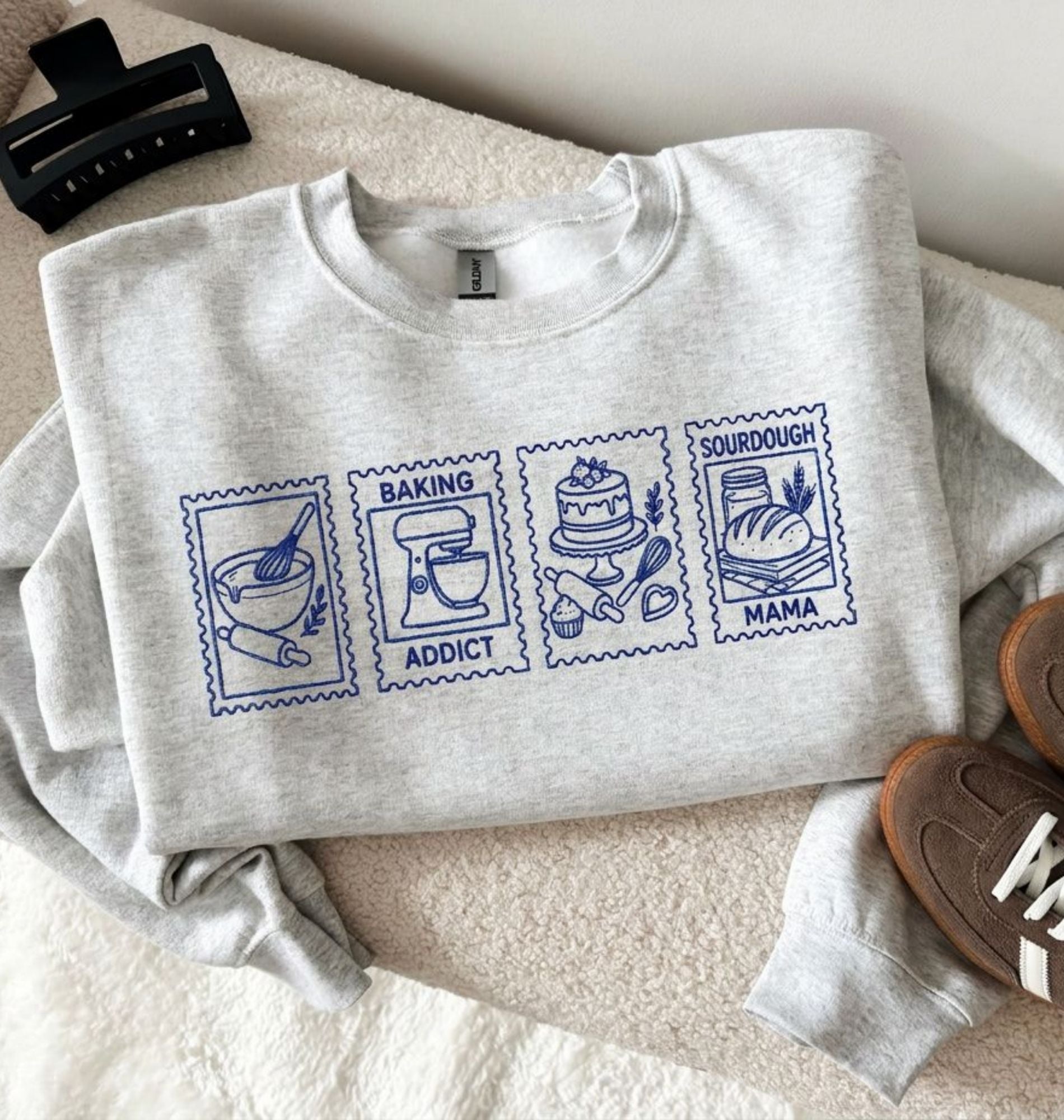 Flat lay of an Embroidered Baking Addict Sourdough Mama sweatshirt with vintage baking stamp design