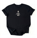 Flat lay of a a Black Comfort Colors shirt featuring an embroidered skeleton whisking ingredients in a mixing bowl on a white background 