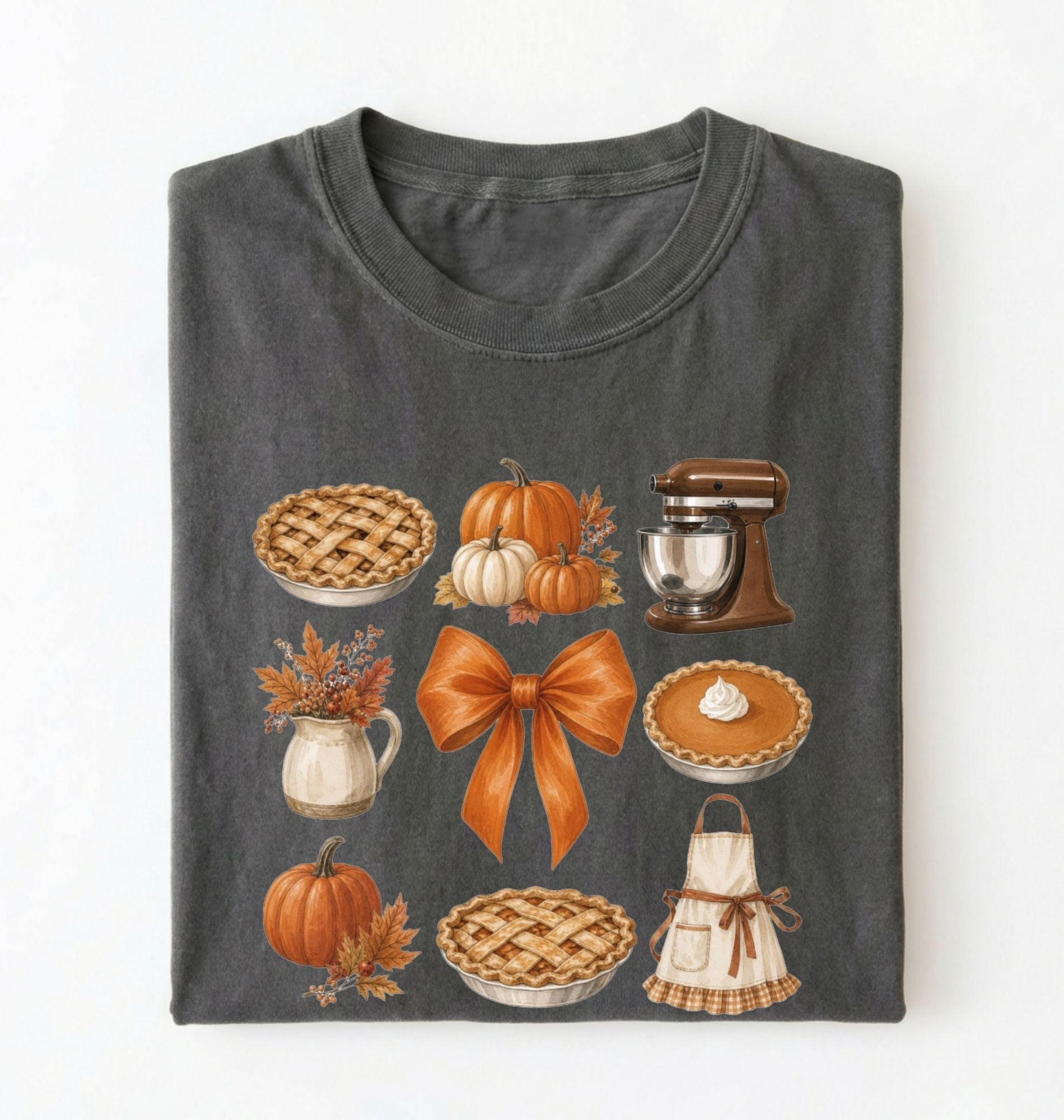 A dark gray folded t-shirt featuring a colorful autumn-themed graphic print with pumpkins, pies, a stand mixer, a bow, and an apron, displayed against a clean white background.
