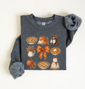 Flat lay of a dark heather fall baking sweatshirt featuring pumpkin pies, pumpkins, autumn leaves, a stand mixer, baking apron and orange bow on a white background 