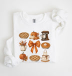 A white long-sleeve crewneck sweatshirt with a cozy autumn-themed graphic print on the front, styled flat on a white background with a matching white knit scarf.