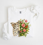 Flat lay of a White Floral ribcage sweatshirt with botanical flowers and butterfly, artistic skeleton plant lover gift on a white background