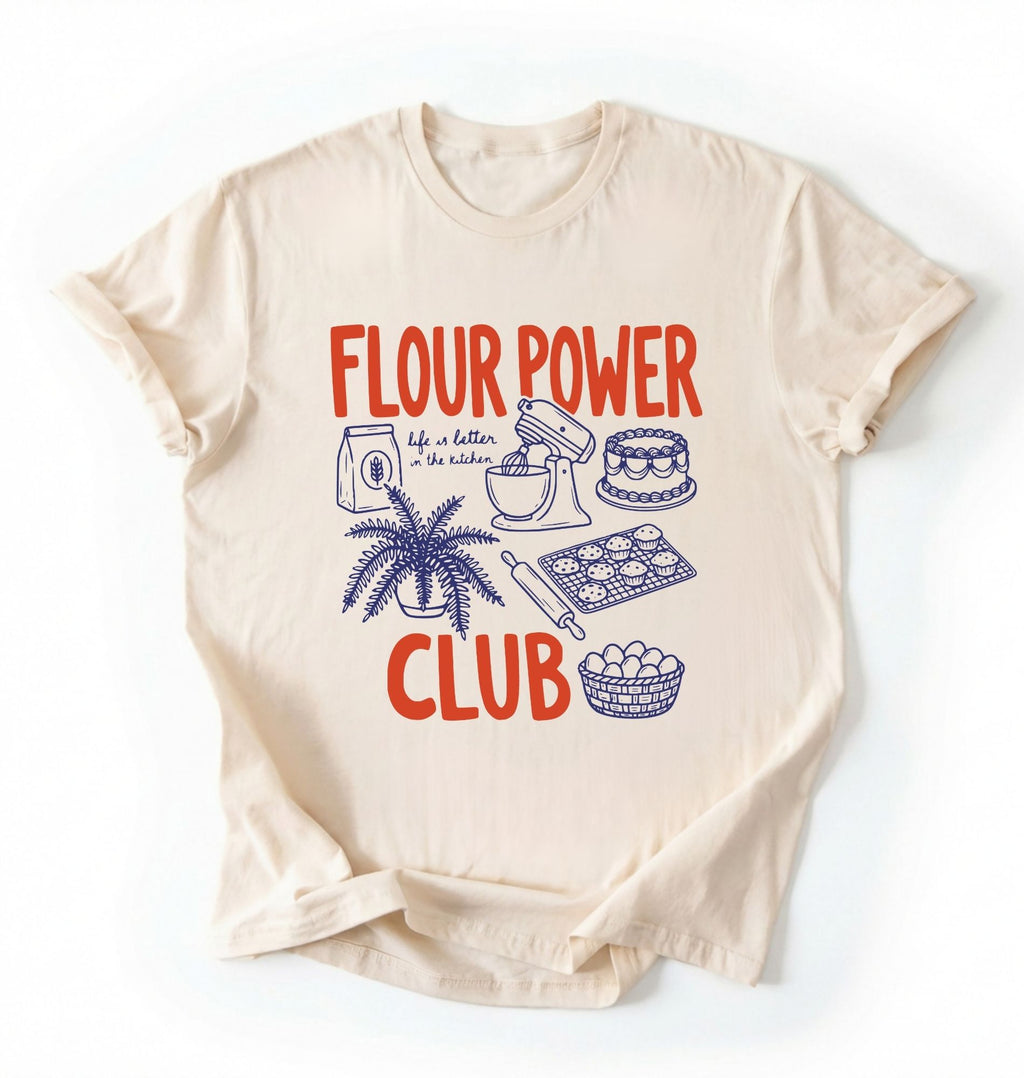 Flat lay of a cream flour power club shirt with stand mixer cake cookies and baking illustrations funny baker gift on a white background 