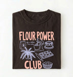 Flat lay of a brown flour power club shirt with stand mixer cake cookies and baking illustrations funny baker gift on a white background 