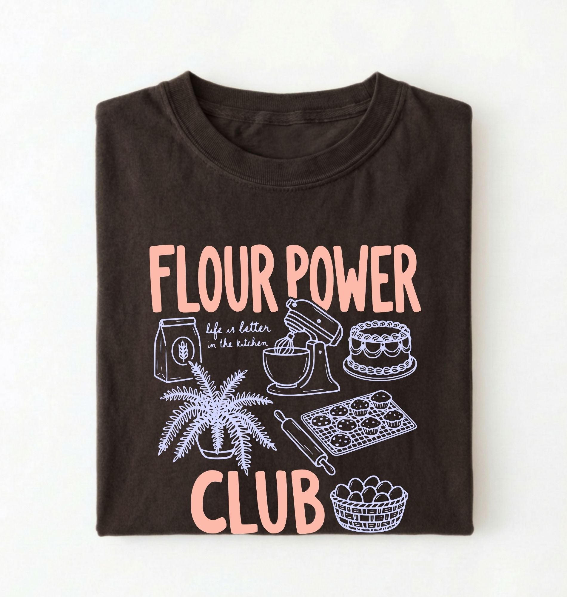 Flat lay of a brown flour power club shirt with stand mixer cake cookies and baking illustrations funny baker gift on a white background 