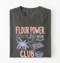 Flat lay of a pepper flour power club shirt with stand mixer cake cookies and baking illustrations funny baker gift on a white background 