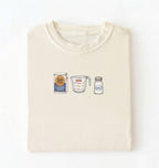 Flat lay of a cream flour water salt shirt with flour bag measuring cup and salt shaker minimalist bread baker gift on a white background 