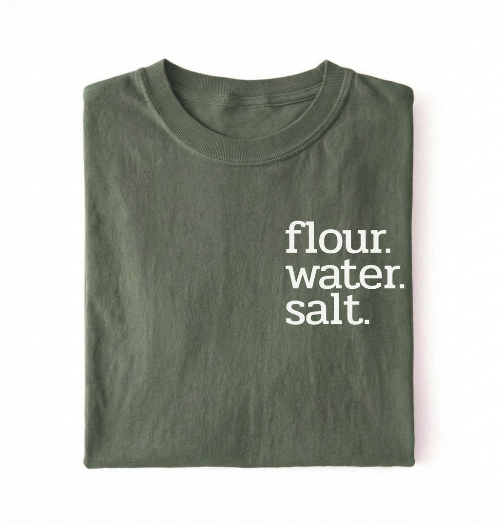 Flat lay of a green flour water salt shirt black minimalist sourdough baking t shirt bread lover gift simple design on a white background 