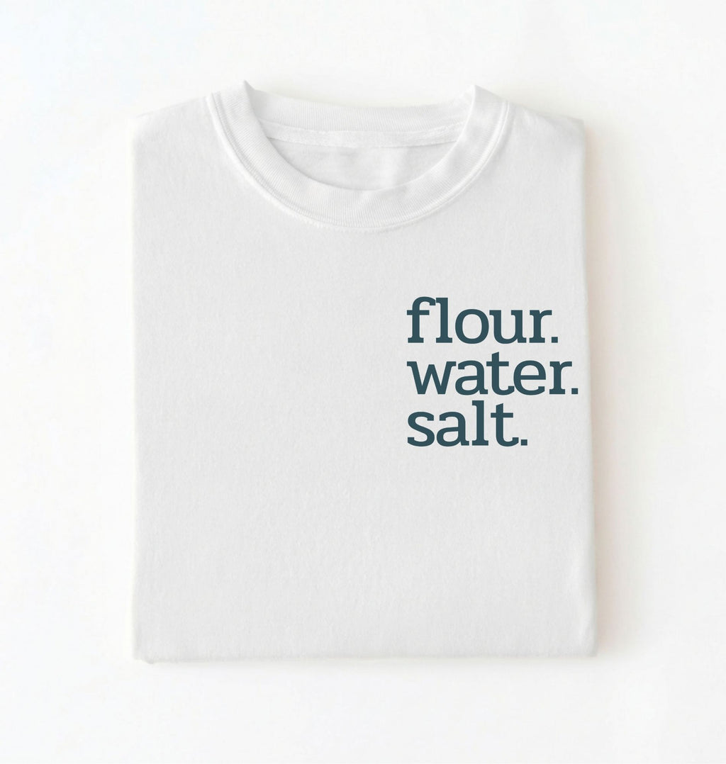 Flat lay of a white flour water salt shirt black minimalist sourdough baking t shirt bread lover gift simple design on a white background 