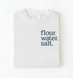 Flat lay of a white flour water salt shirt black minimalist sourdough baking t shirt bread lover gift simple design on a white background 