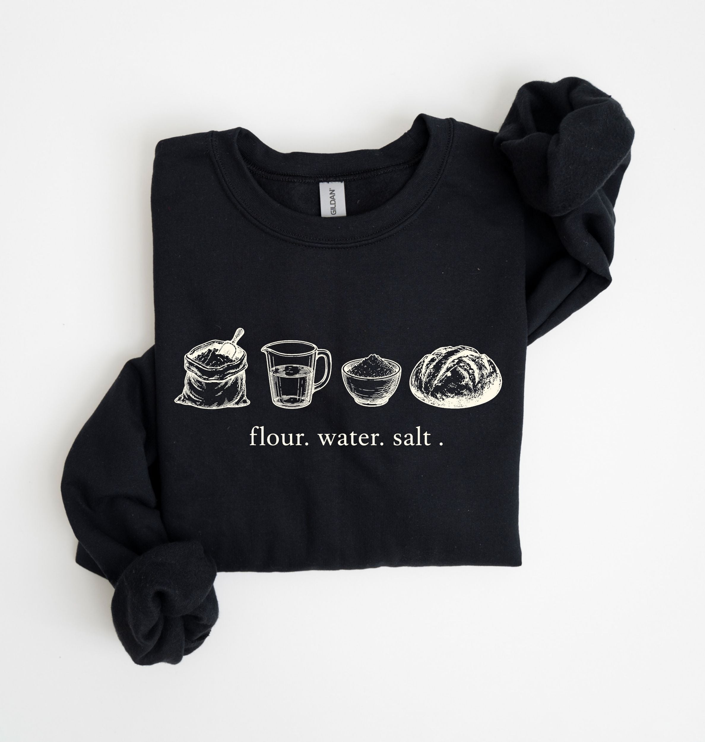 A black long-sleeve sweatshirt with rolled cuffs, featuring a white graphic of flour, water, and salt ingredients with the text 'flour. water.