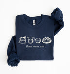 A navy sourdough sweatshirt featuring vintage illustrations of flour, water, salt and a freshly baked bread loaf on a white background