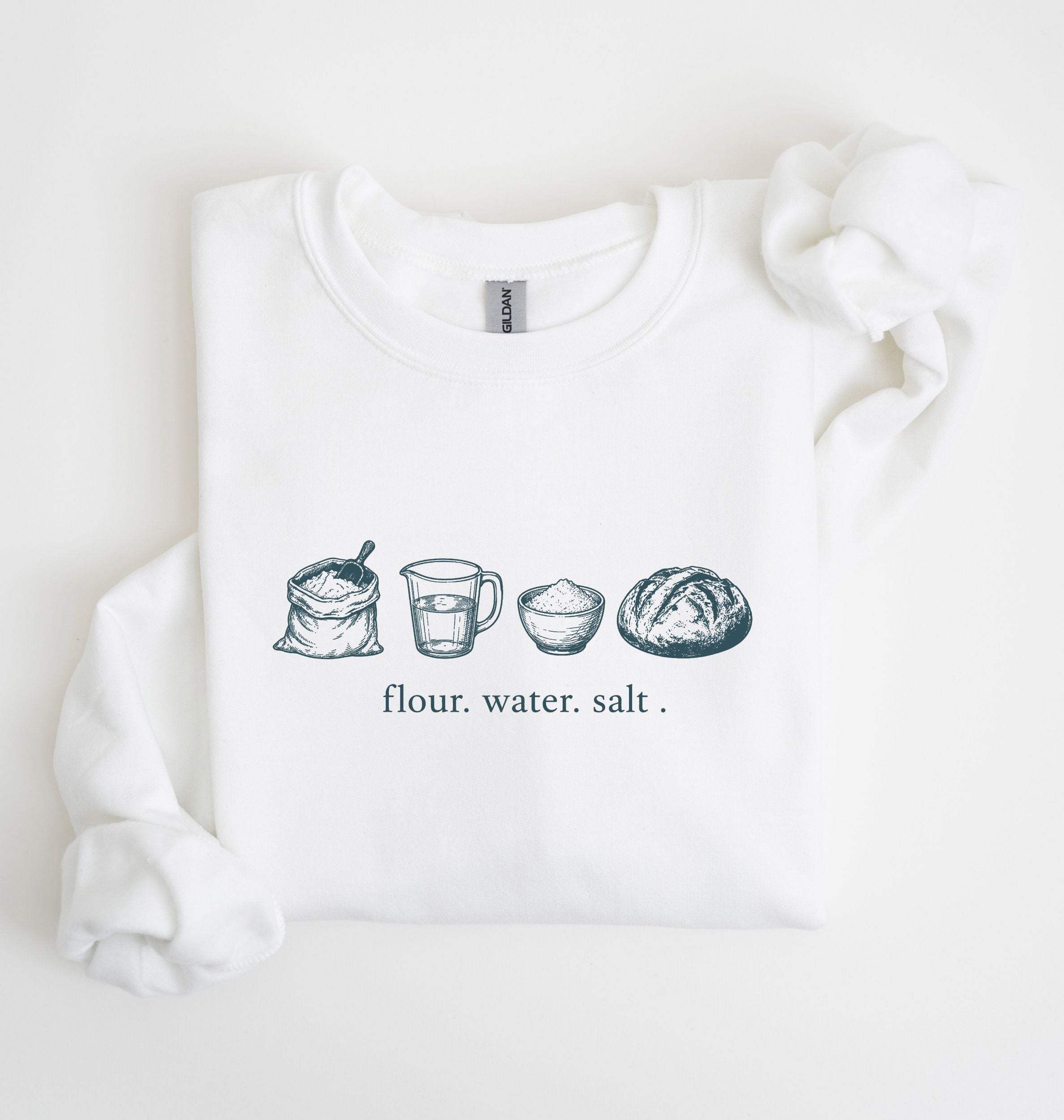 A white crewneck sweatshirt featuring a graphic print of various baking ingredients (bowl, flour, butter, sugar, vanilla, eggs, measuring cup) arranged in a row, displayed on a clean white background.