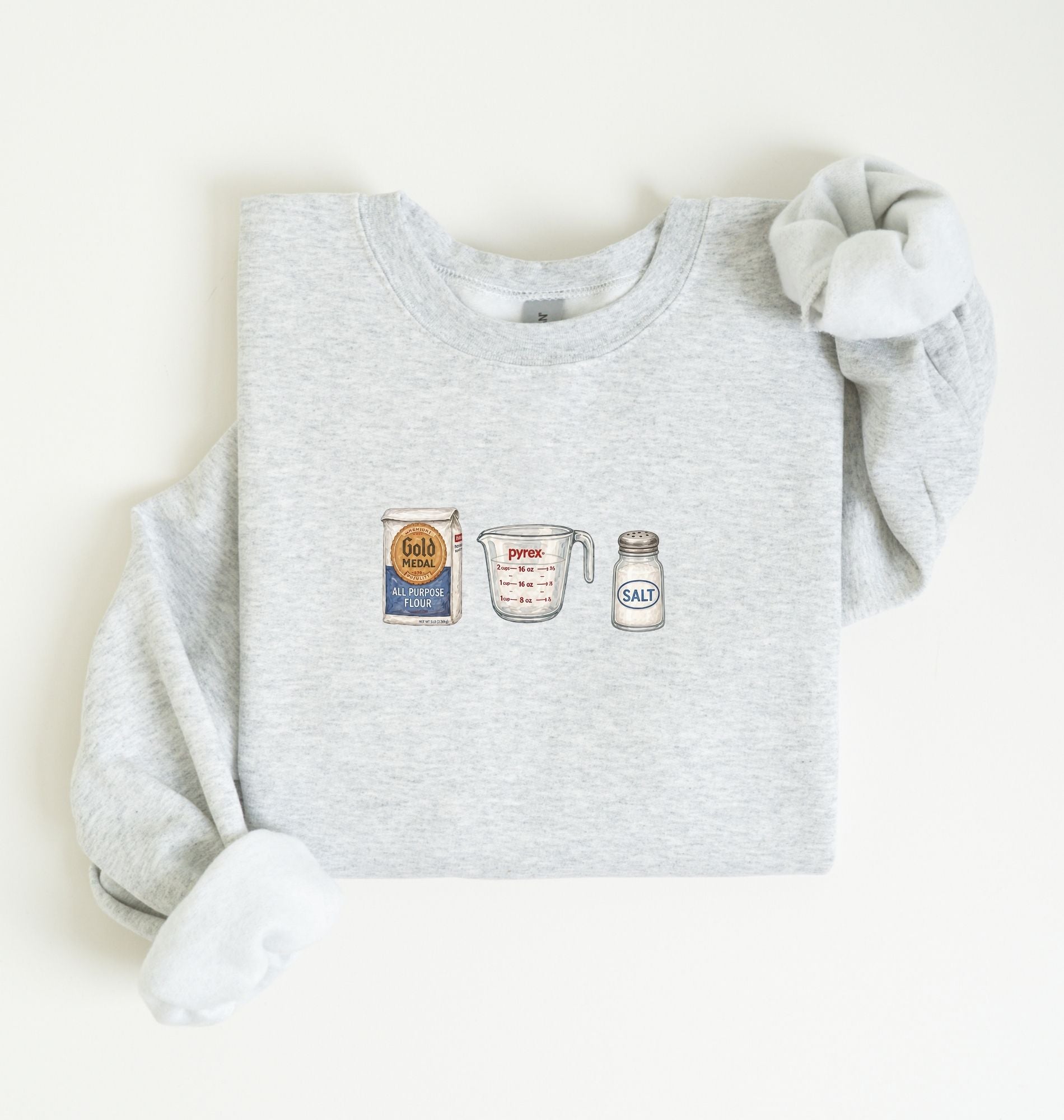 Flat lay of an ash flour water salt sweatshirt with flour bag measuring cup and salt shaker for bread bakers on a white background 