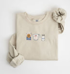 Flat lay of a sand flour water salt sweatshirt with flour bag measuring cup and salt shaker for bread bakers on a white background 