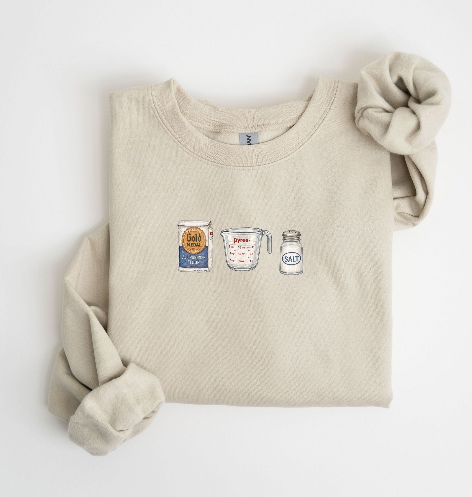 Flat lay of a sand flour water salt sweatshirt with flour bag measuring cup and salt shaker for bread bakers on a white background 