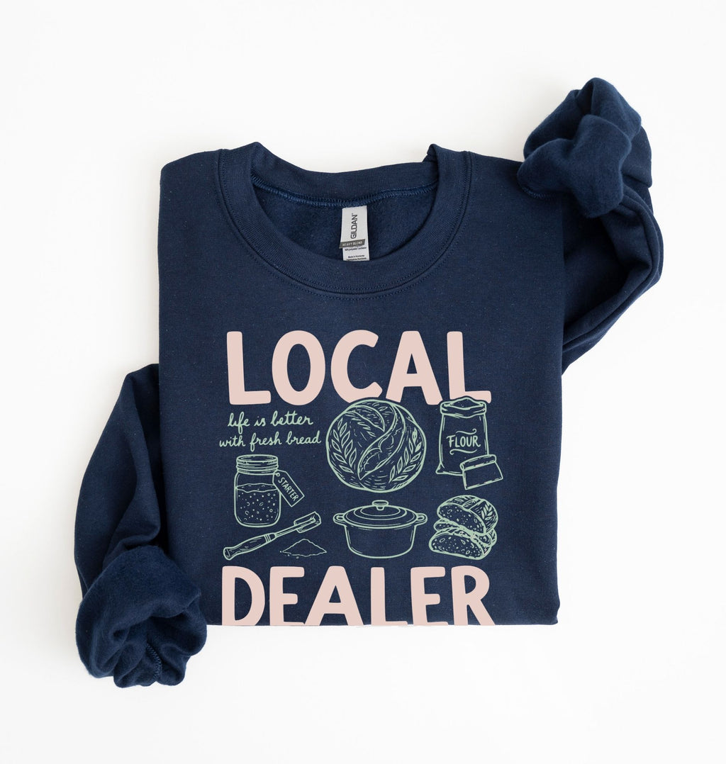 Flat lay of an navy cottagecore baking sweatshirt with Local Dealer text and bread graphics gift for bakers on a white background 