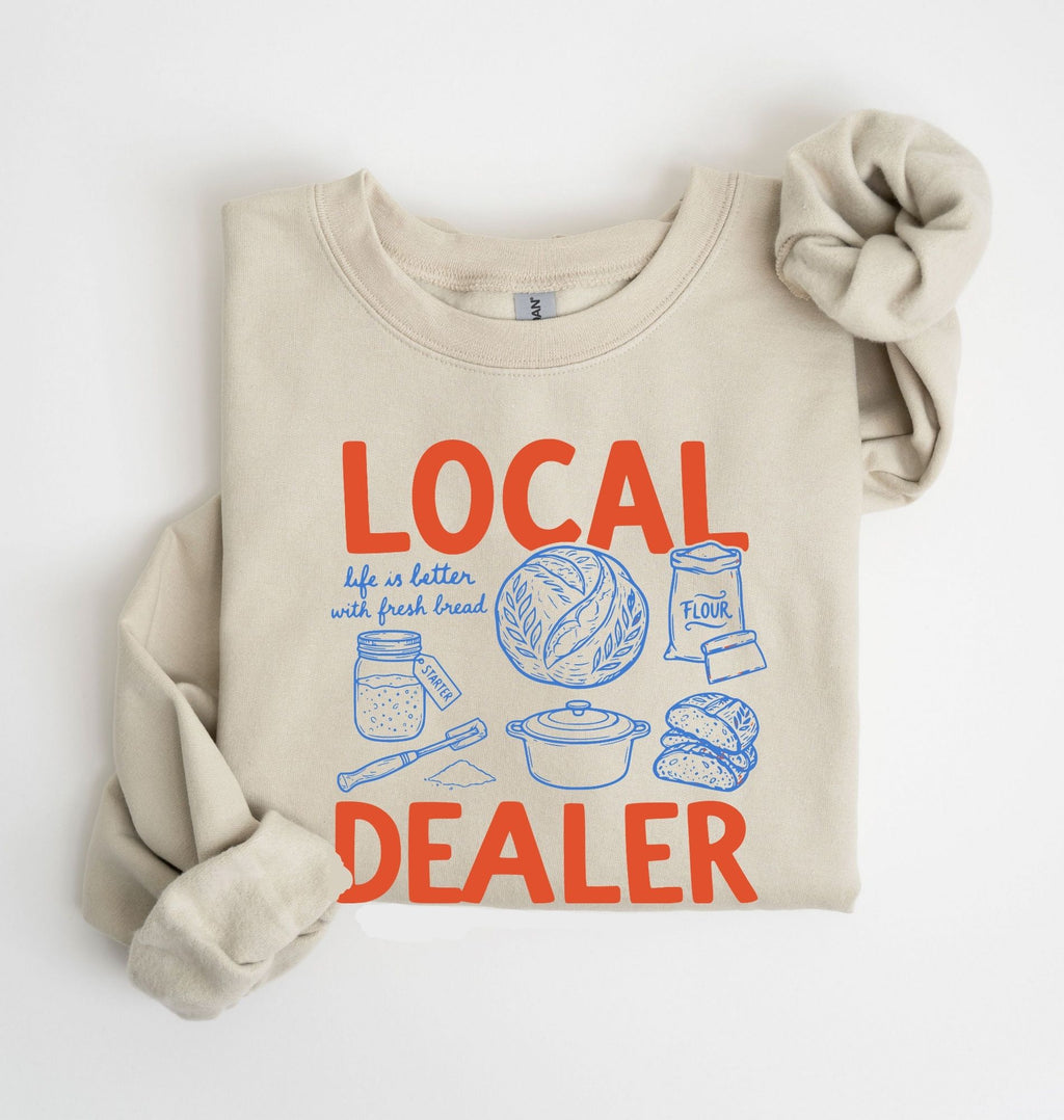 Flat lay of an sand cottagecore baking sweatshirt with Local Dealer text and bread graphics gift for bakers on a white background 