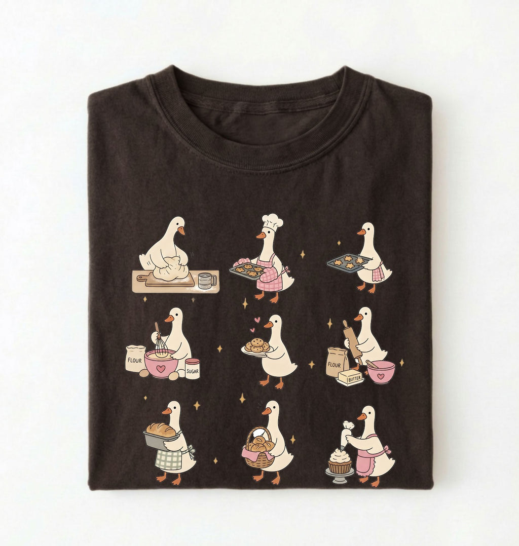 Flat lay of a Cute goose baking shirt with cottagecore bread baking illustrations on brown tee on a white background 