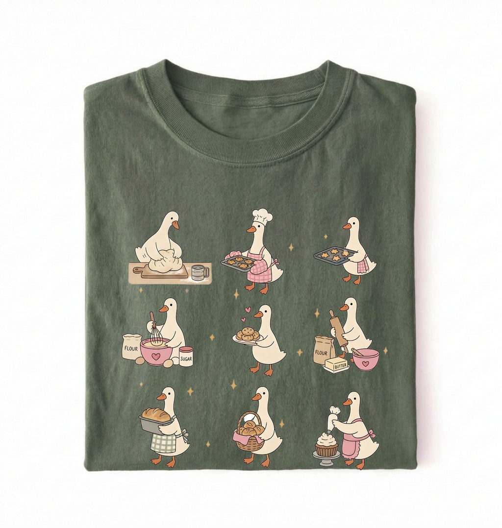 Flat lay of a Cute goose baking shirt with cottagecore bread baking illustrations on green tee on a white background 
