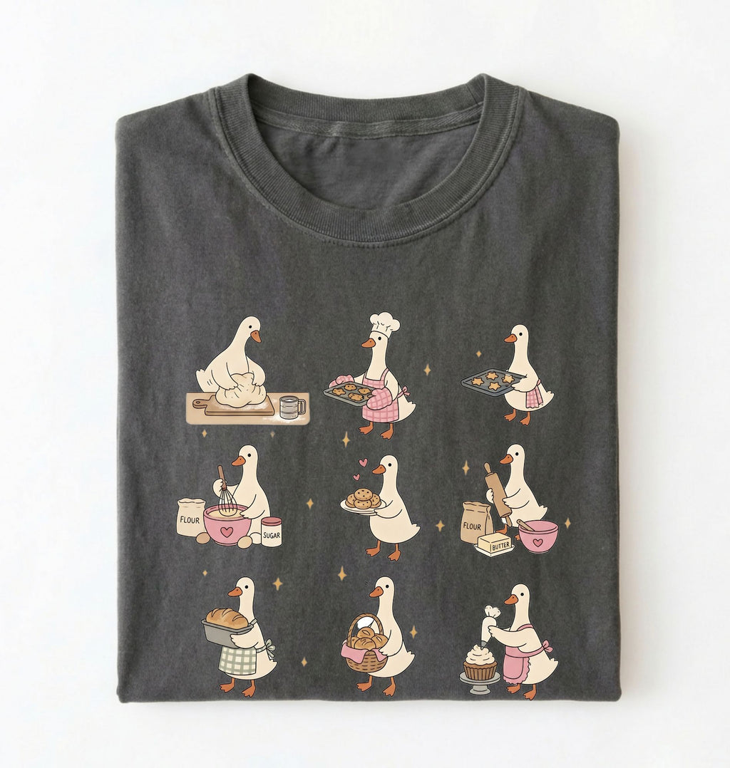 Flat lay of a Cute goose baking shirt with cottagecore bread baking illustrations on pepper tee on a white background 