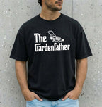 Person wearing a black t-shirt with 'The Gardenfather' text and graphic against a gray concrete wall.