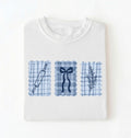 Flat lay of a white Cottagecore baking shirt with blue gingham pattern and baking icons perfect gift for bakers and vintage kitchen lovers on a white background 