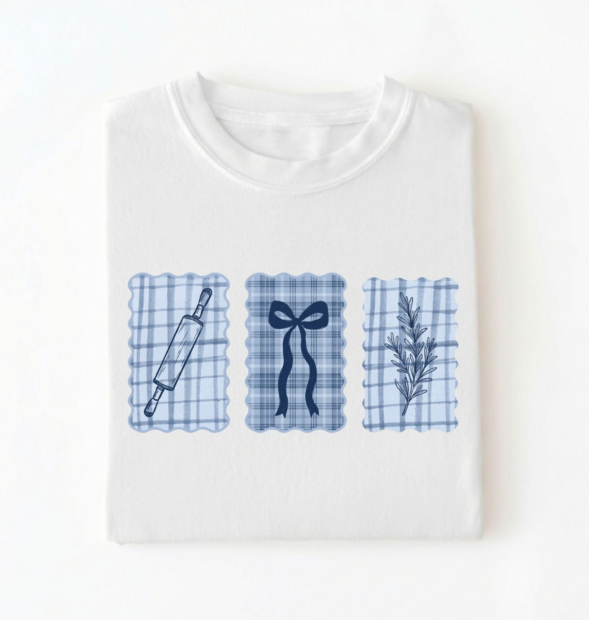 Flat lay of a white Cottagecore baking shirt with blue gingham pattern and baking icons perfect gift for bakers and vintage kitchen lovers on a white background 