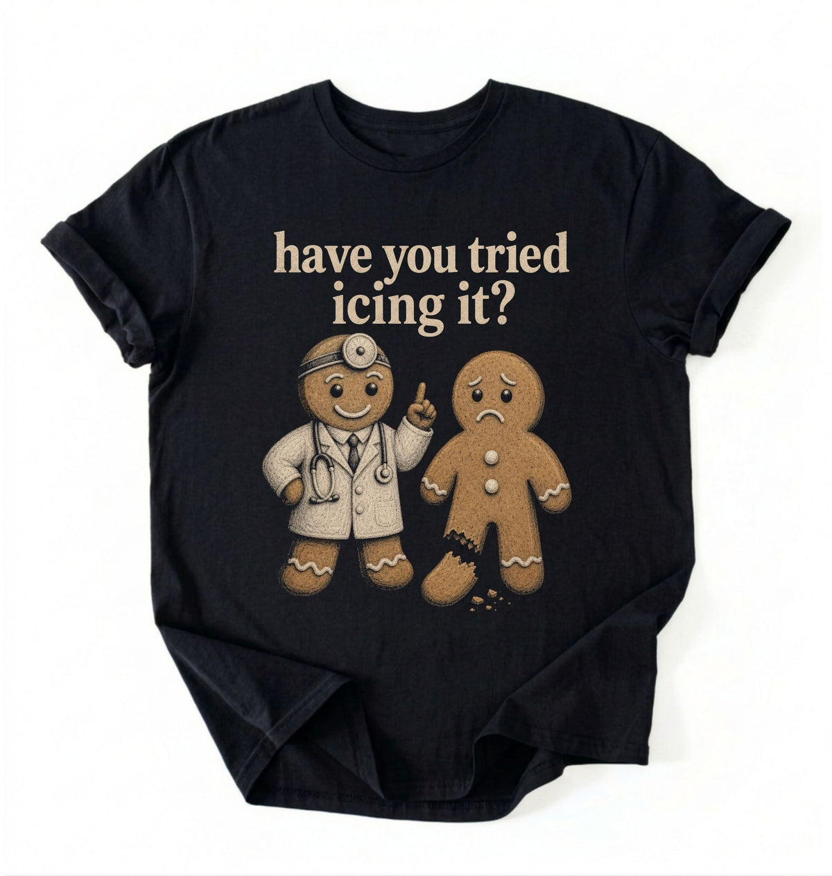 A black short-sleeve graphic t-shirt laid flat on a white background. The shirt features a graphic of a gingerbread man in a white doctor's coat pointing upwards next to a sad gingerbread man, with the text 'have you tried icing it?' printed above them in a beige retro font.